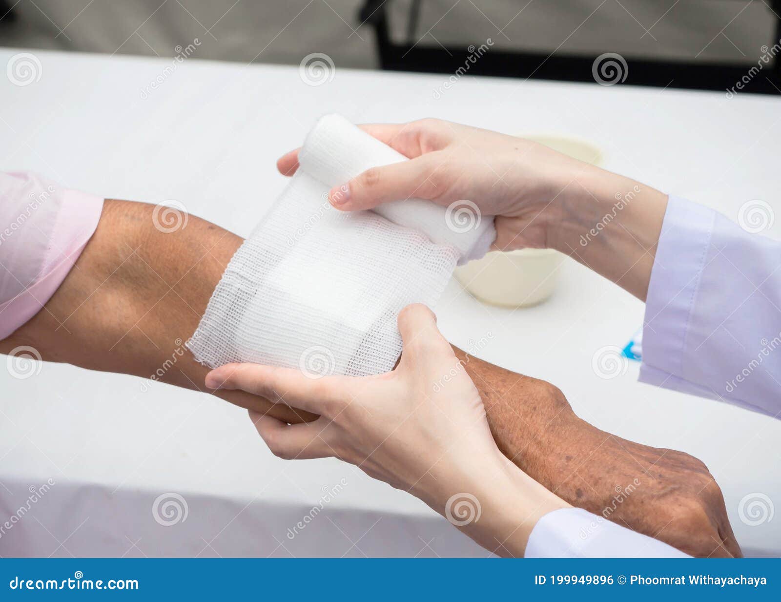 closeup wound dressing an elderly person. doctor suing bandage covering on senior womanÃ¢â¬â¢s arm at home, wearing glove to protect