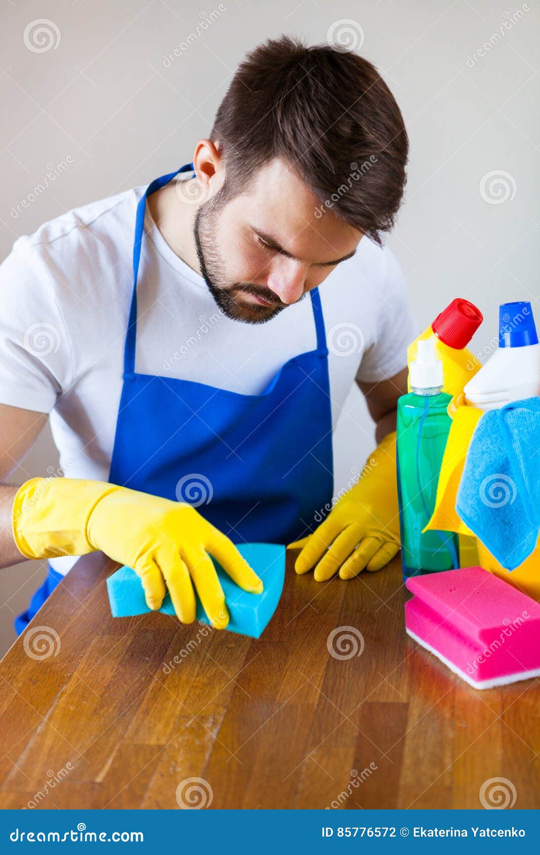 Closeup of Young Man Wearing Apron Cleaning Kitchen Worktop Stock Photo