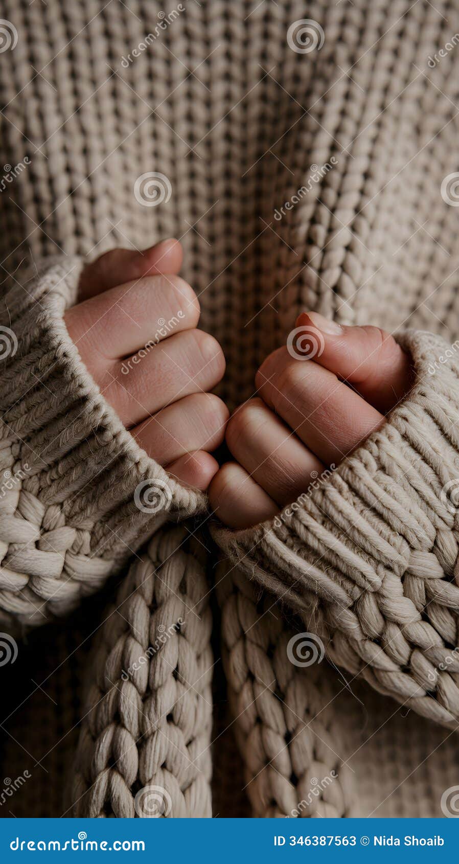 hands hold thick beige fabric, conveying warmth and comfort in cozy setting.