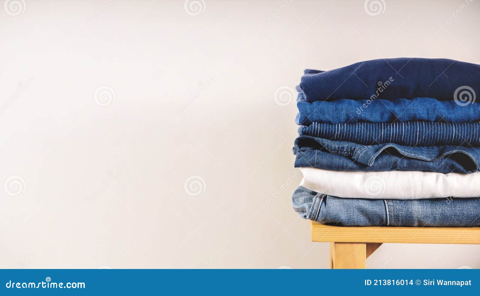 Clothes Concept. Stack of Clothing on Wooden Bench by the White Wall ...