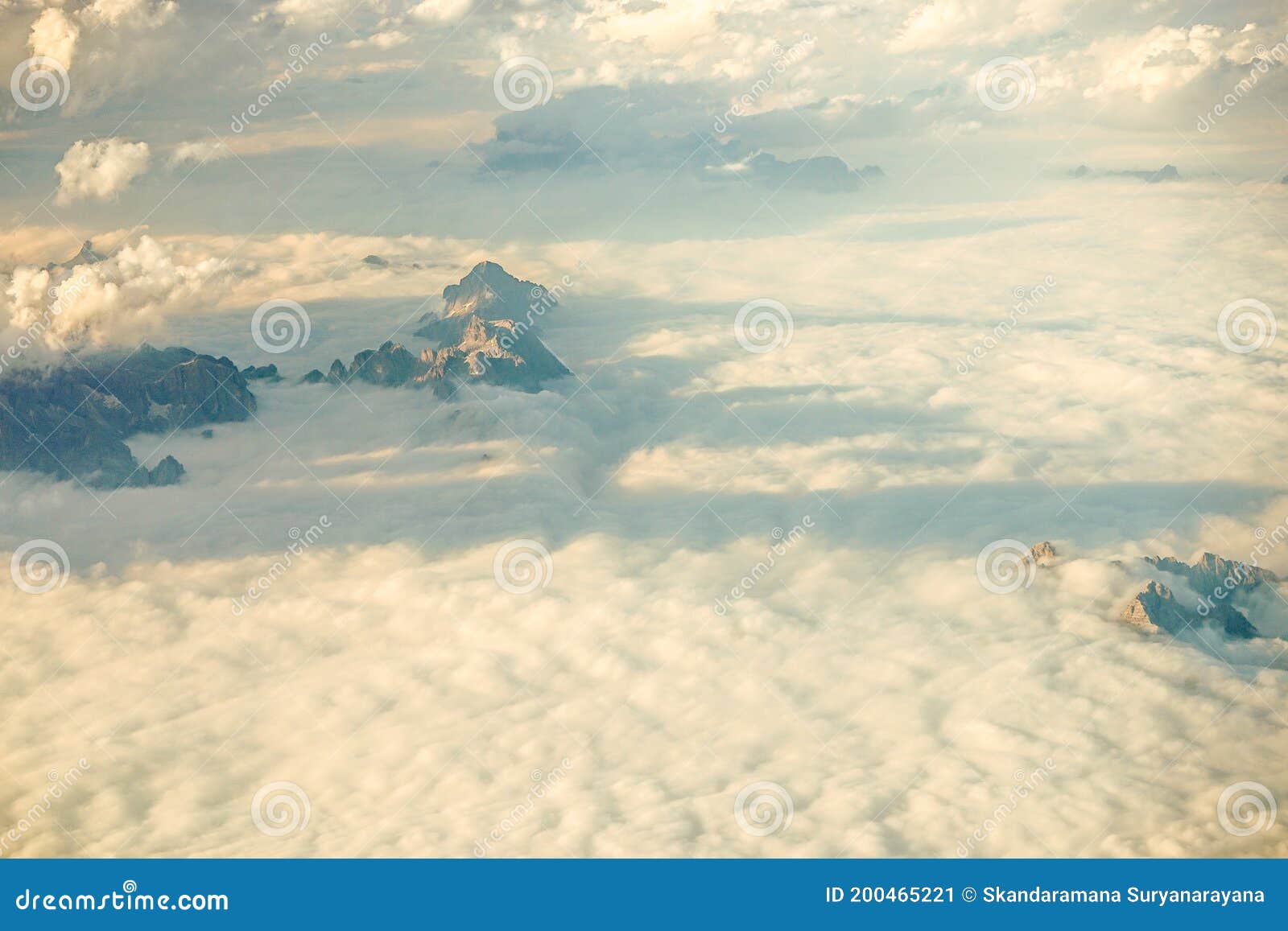 clouds over snow clad austrian alps mountains seen from an airplane window