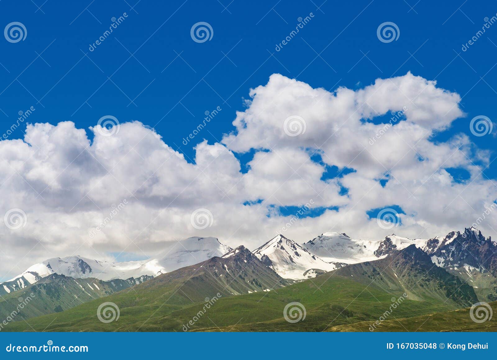 Majestic Snow Capped Mountain Peak with Green Alpine Meadows Stock