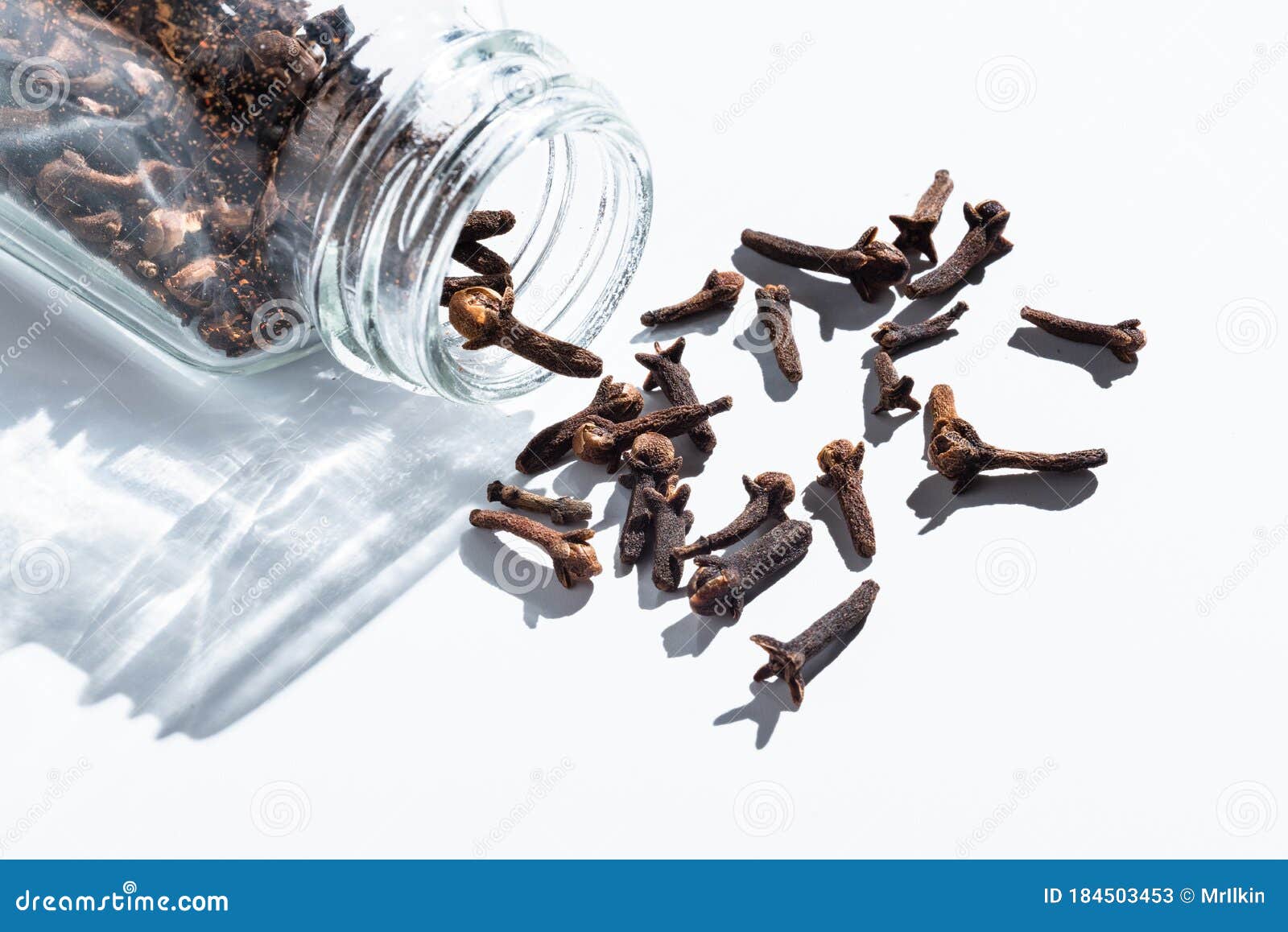 Cloves are Scattered from a Glass Jar. Spice on White Stock Image