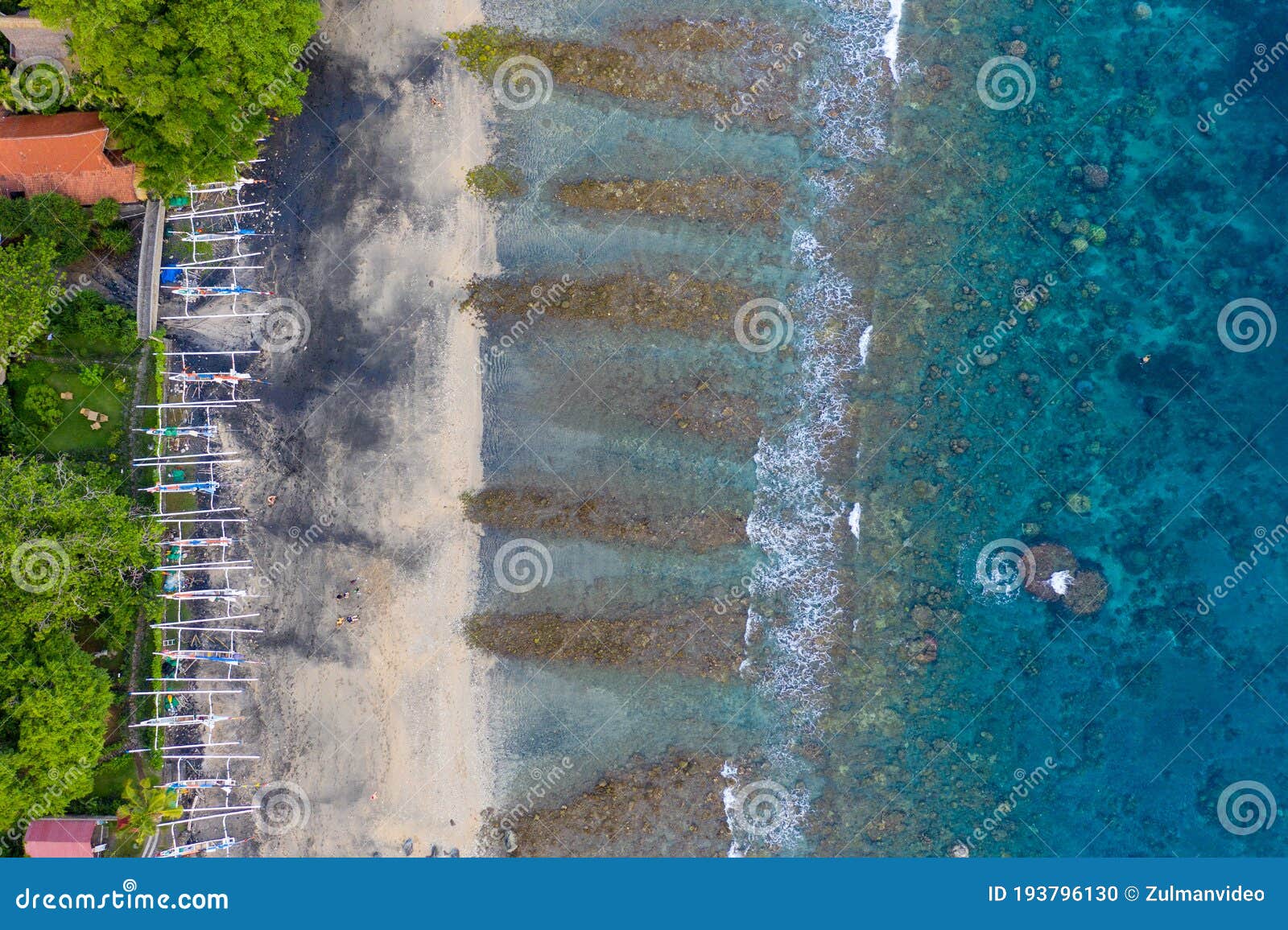 coastline of amed, bali. beach with stones and fishing boats. aerial view.