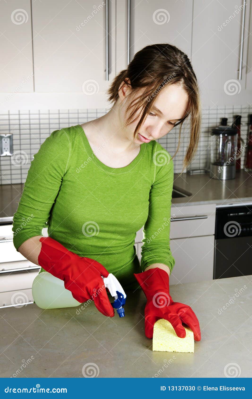 Cocina de la limpieza de la muchacha con los guantes de la esponja y del caucho