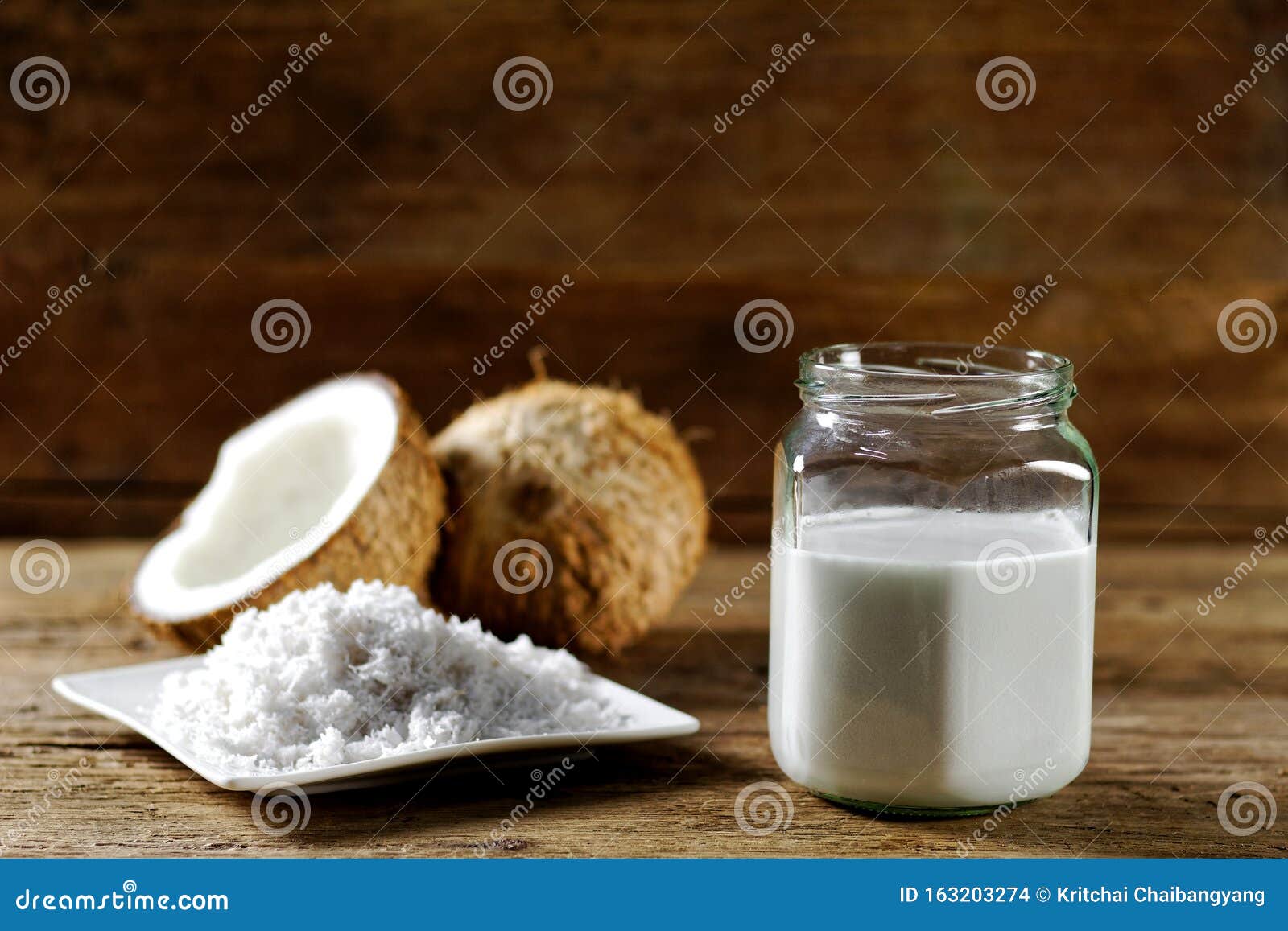 Coconut Milk in a Jar with Full and Half Coconut Fruit on Dark Wooden