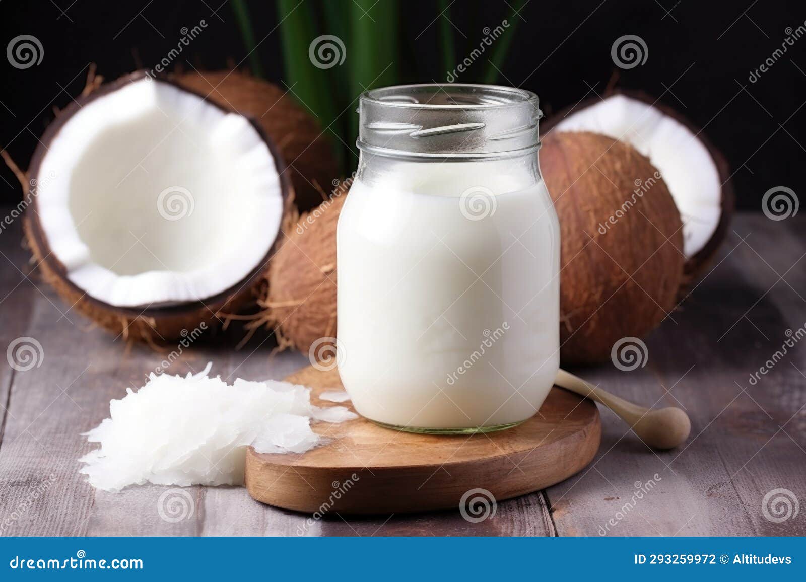 Coconut Oil in a Glass Jar with a Stack of Fresh Coconuts in the