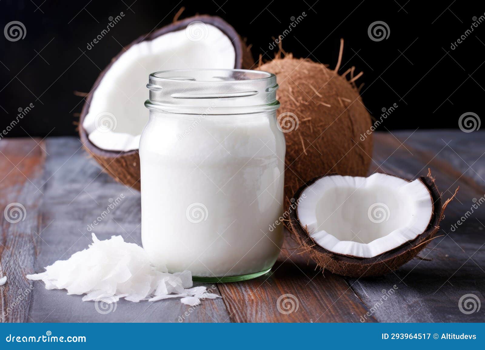 Coconut Oil in a Glass Jar with a Stack of Fresh Coconuts in the