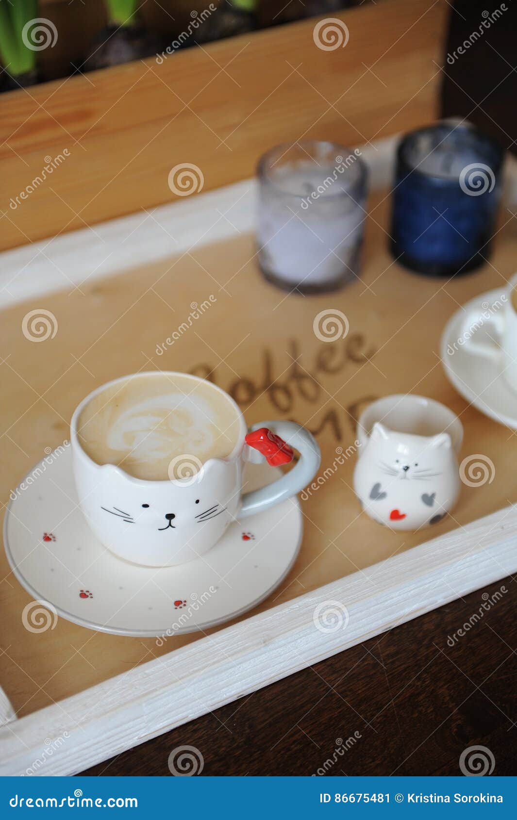 coffee cappuccino in cute cup in the  of cat. on a wooden tray. candles on the background