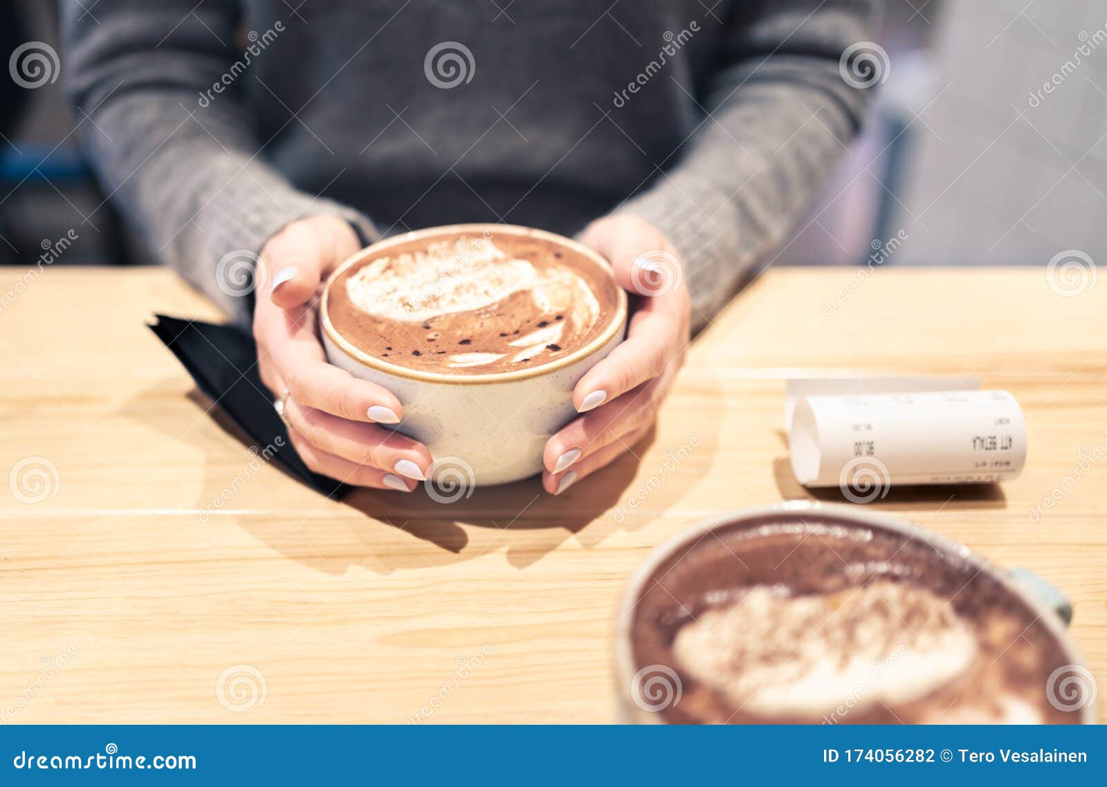 coffee cup between hands in cafe in winter. cappuccino, macchiato, latte or hot chocolate cocoa. two persons having a warm meeting