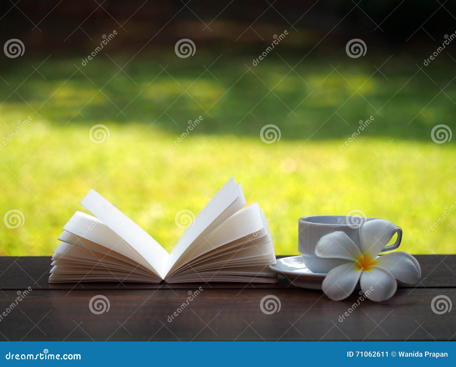 coffee cup and open book with flower on wooden table ,soft focus