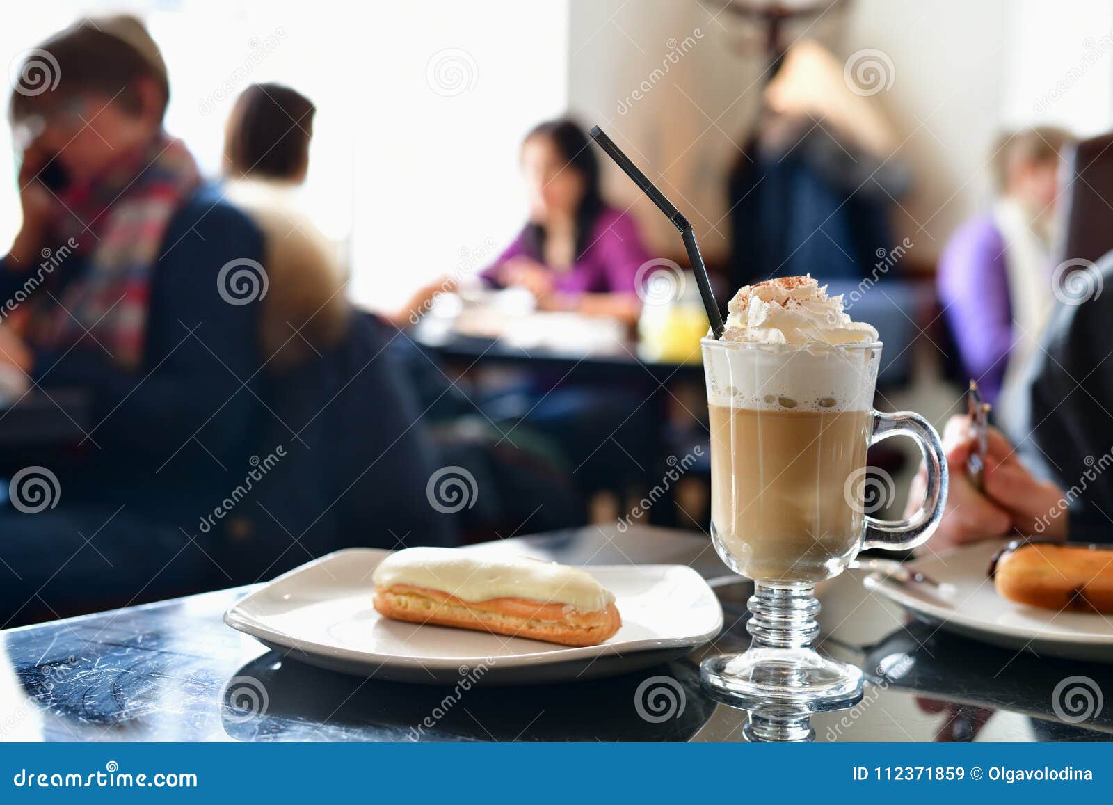 Coffee with Whipped Cream and Eclair on Table in a Cafe Stock Image