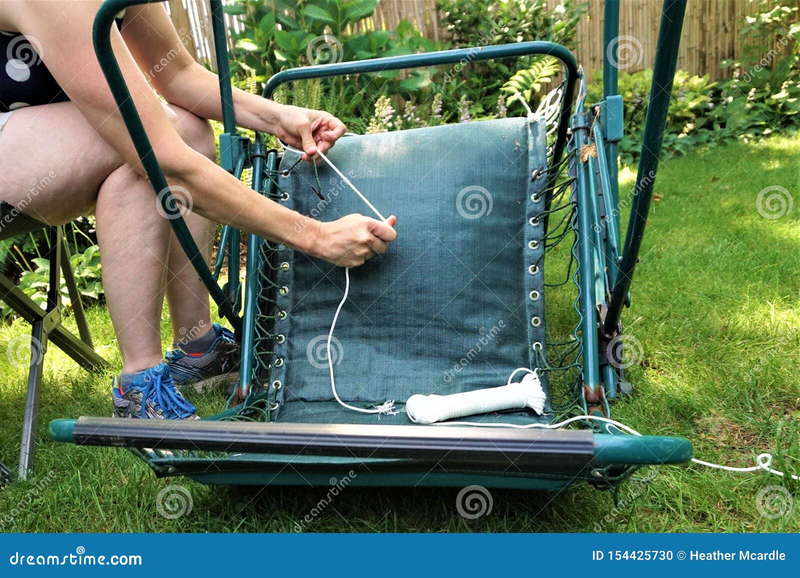 Woman Fixing Lawn Chair Do it Yourself Project on Lawn Stock Photo