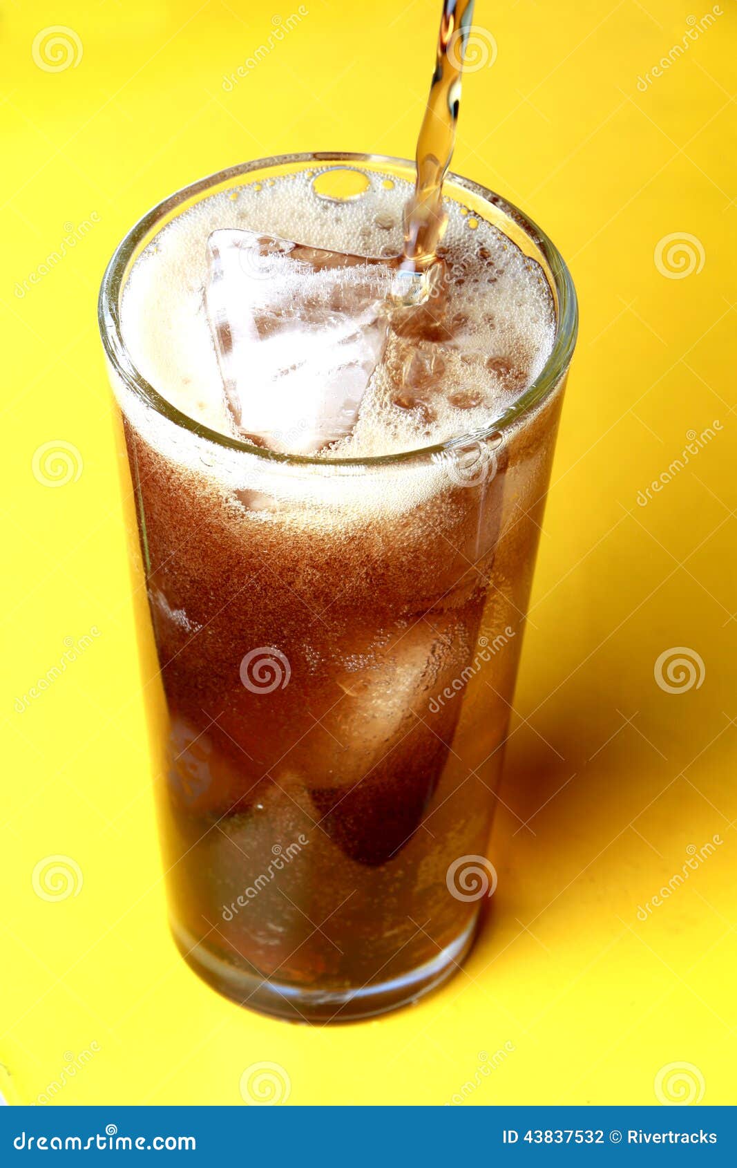 cola soda poured into a glass with ice cubes