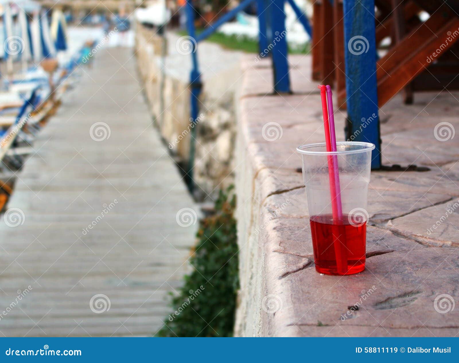 Photo of cold red drink with straw at the beach