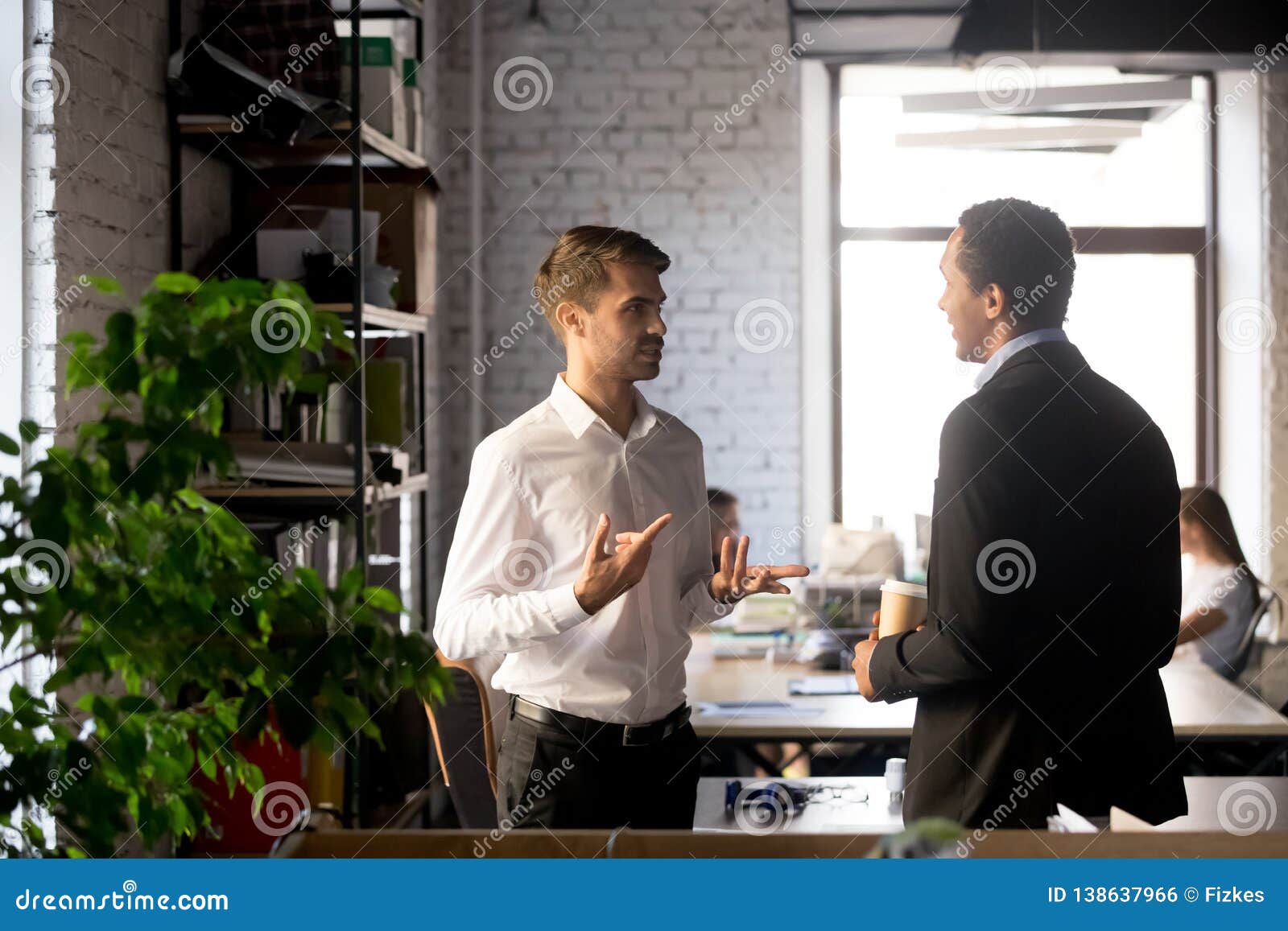 colleagues standing having casual conversation in office