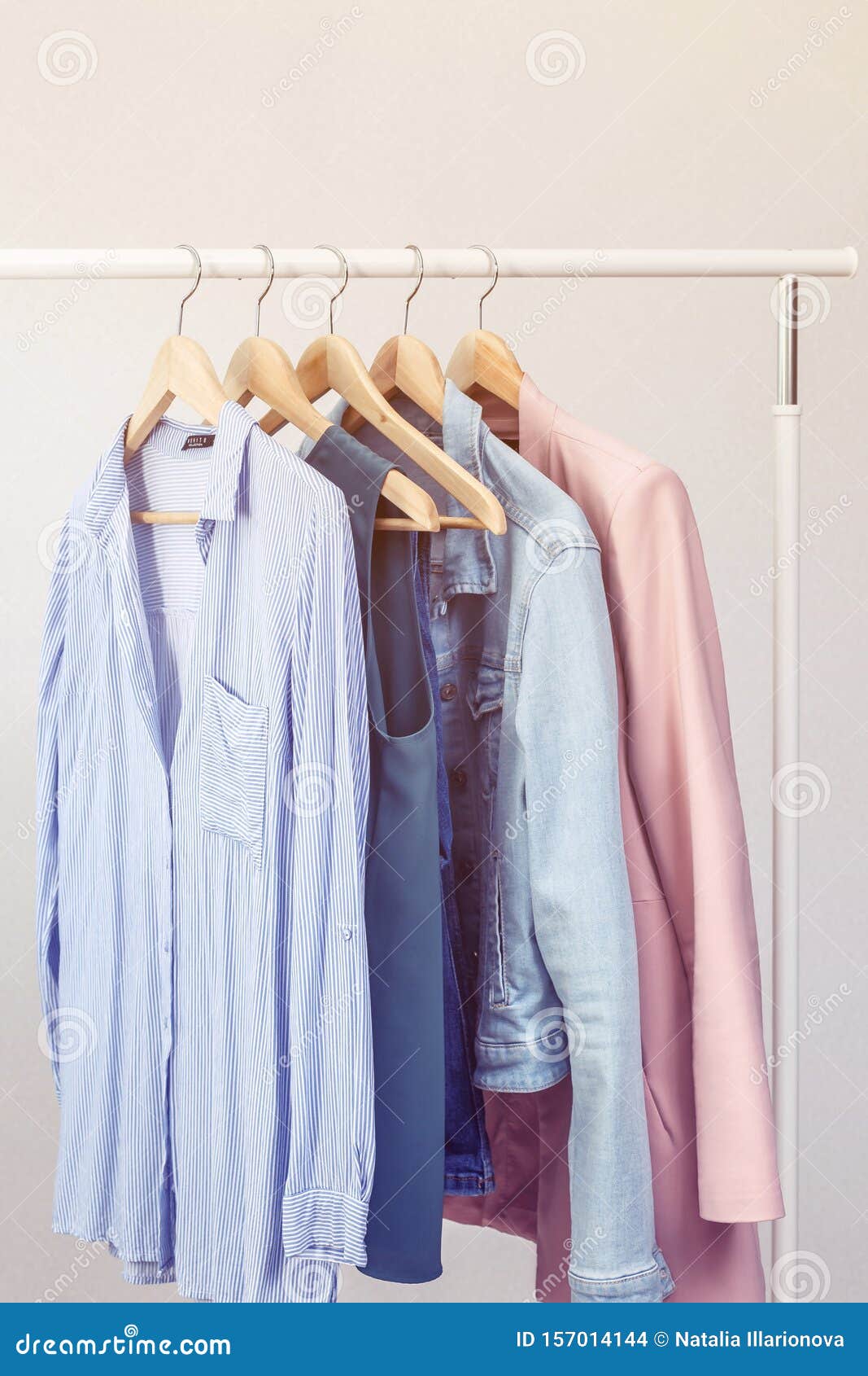 Collection of Clothes Hanging on Rack Near White Wall. Stock Photo ...