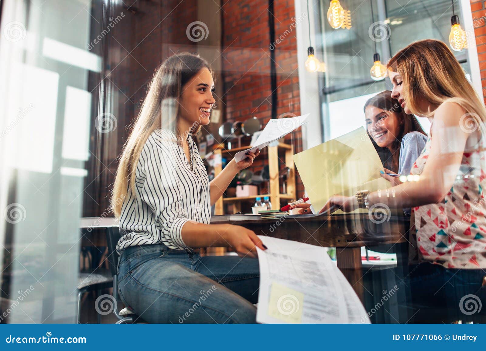college female students sitting at table working on school assignment in a library