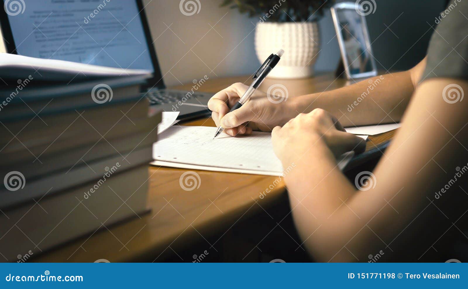 college or university student doing school homework at home. working late at night. young woman writing on paper with pen.