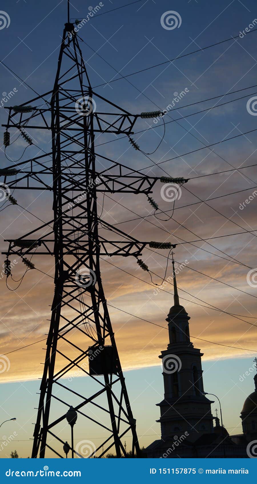 Colonna con le linee elettriche e tempio contro l'alba Russia del cielo