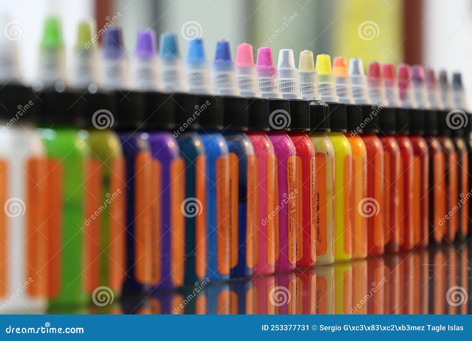 colored inks in plastic containers formed in a row and bokeh background