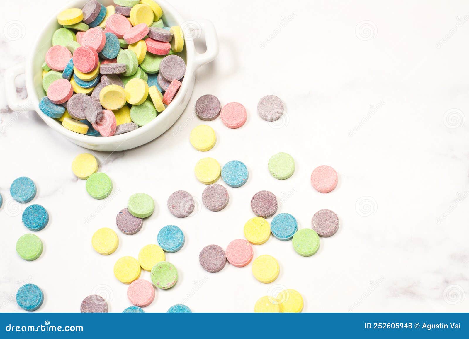 Colored Tablet Candies in a White Bowl on a Marble Kitchen Counter