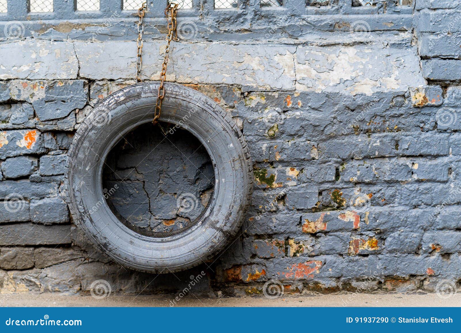 Colored Tires Hanging on the Chain Have a Brick Wall Stock Photo