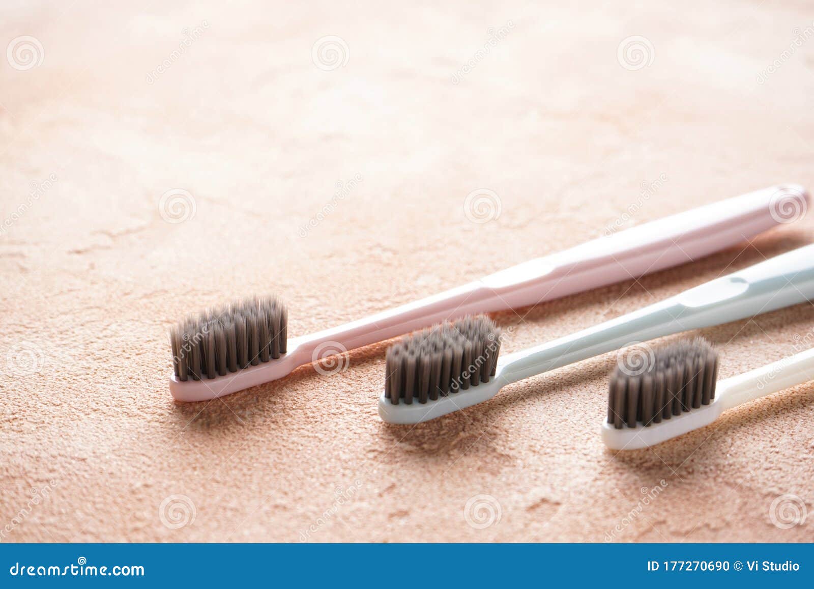 Colored Toothbrushes with Black Bristles on a Beige Background Stock