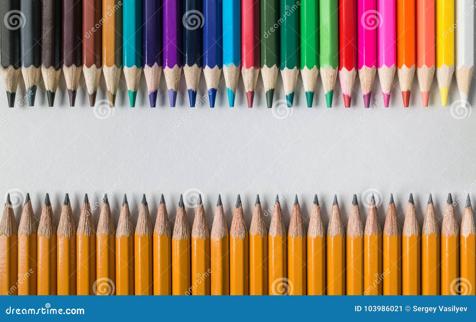 colored wood pencils in front of simple graphite pencils on table 