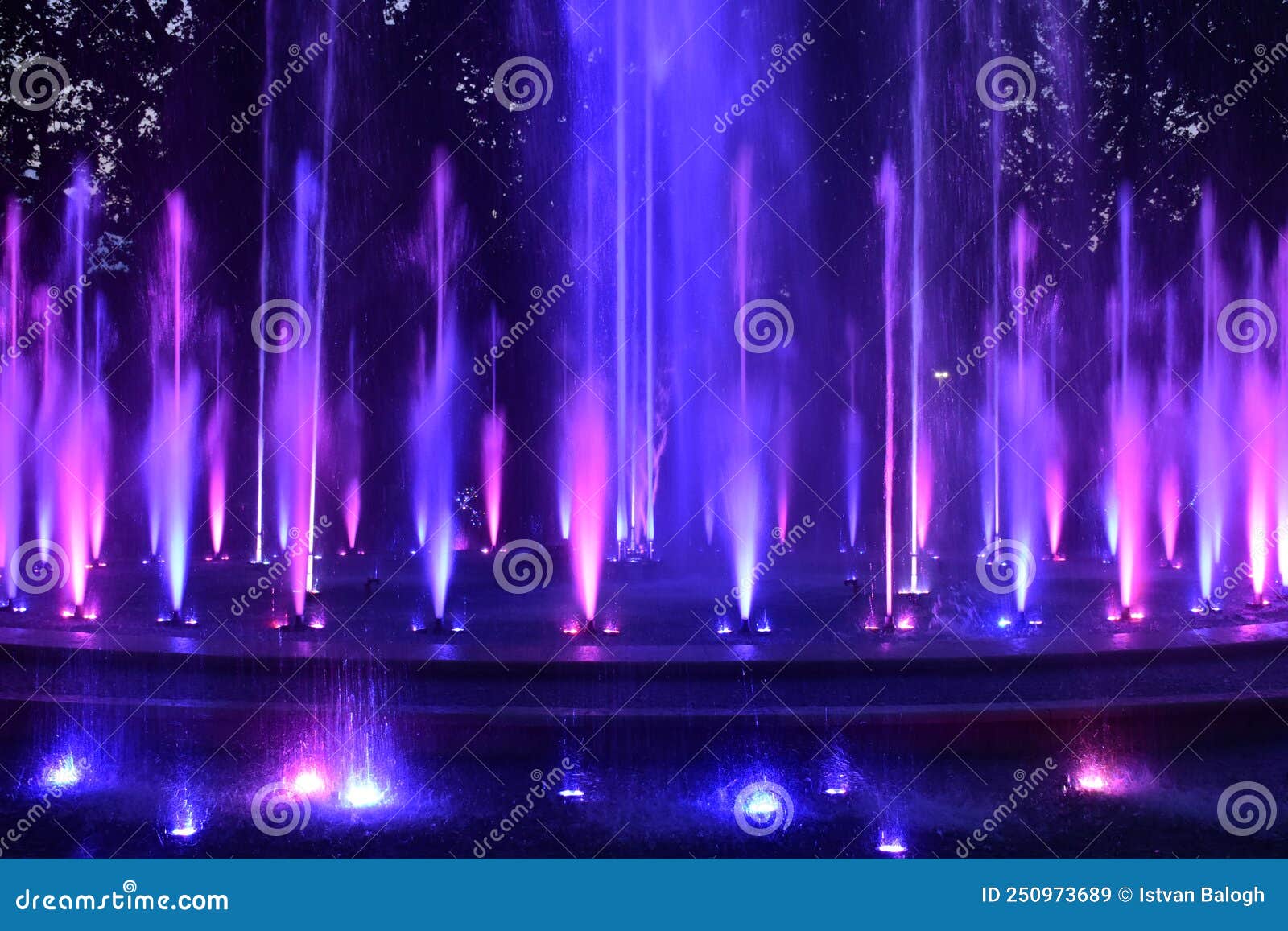 colorful purple, pink blue color water jets at public fountain