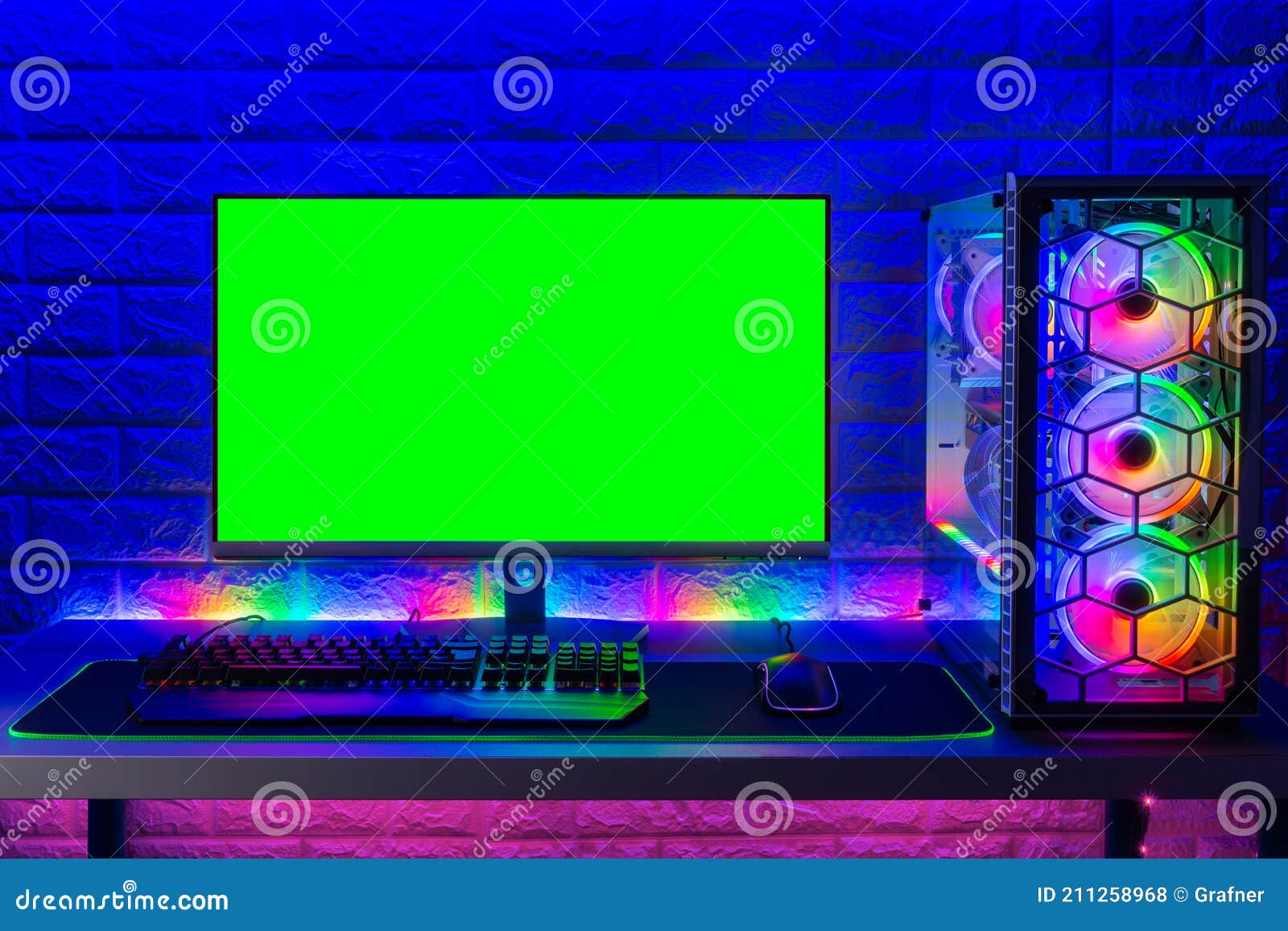 colorful bright illuminated rgb gaming pc with keyboard mouse monitor with green screen copy space front of led light brick stone