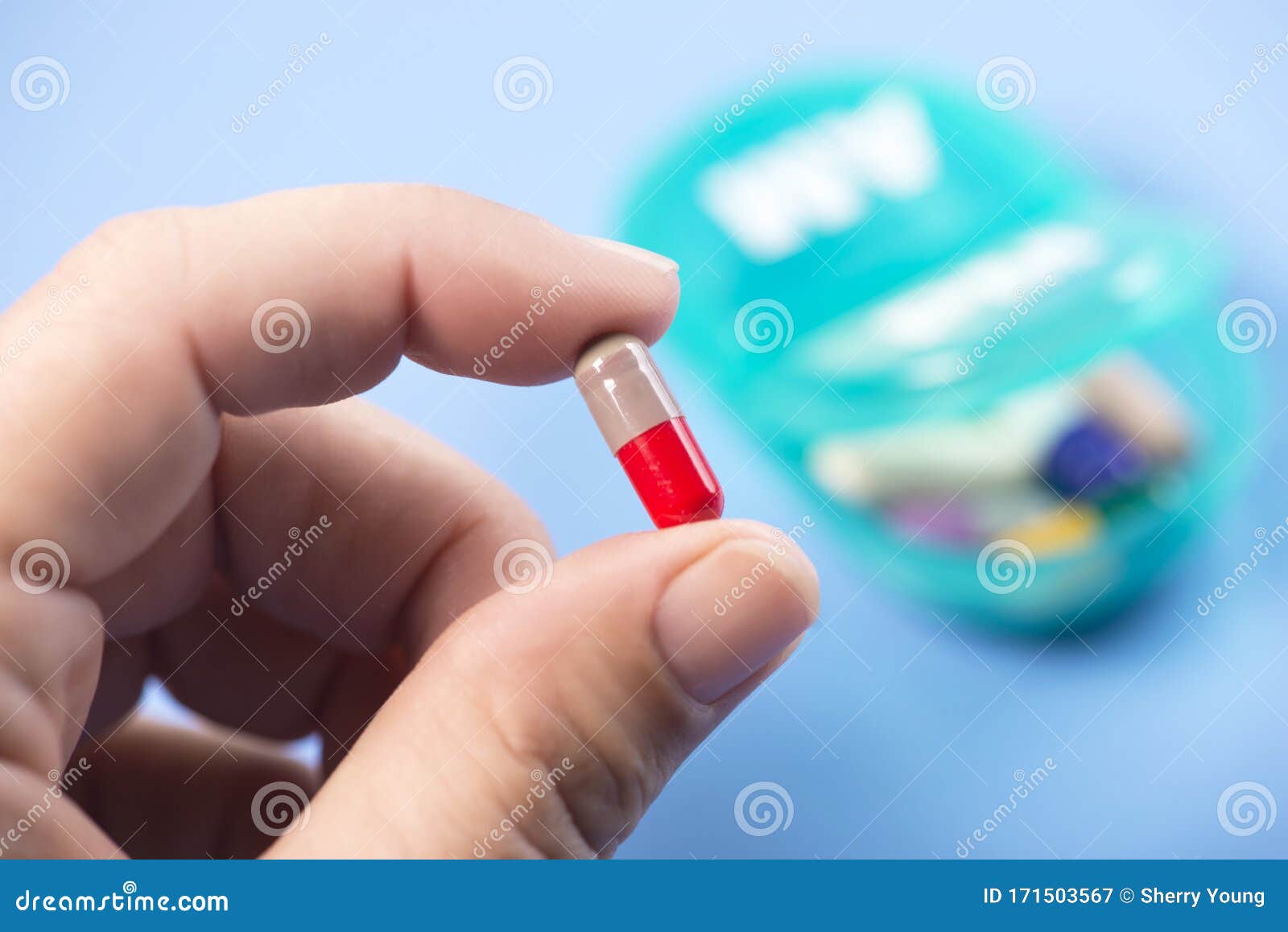 colorful capsule in patient hand with daily pill dispenser