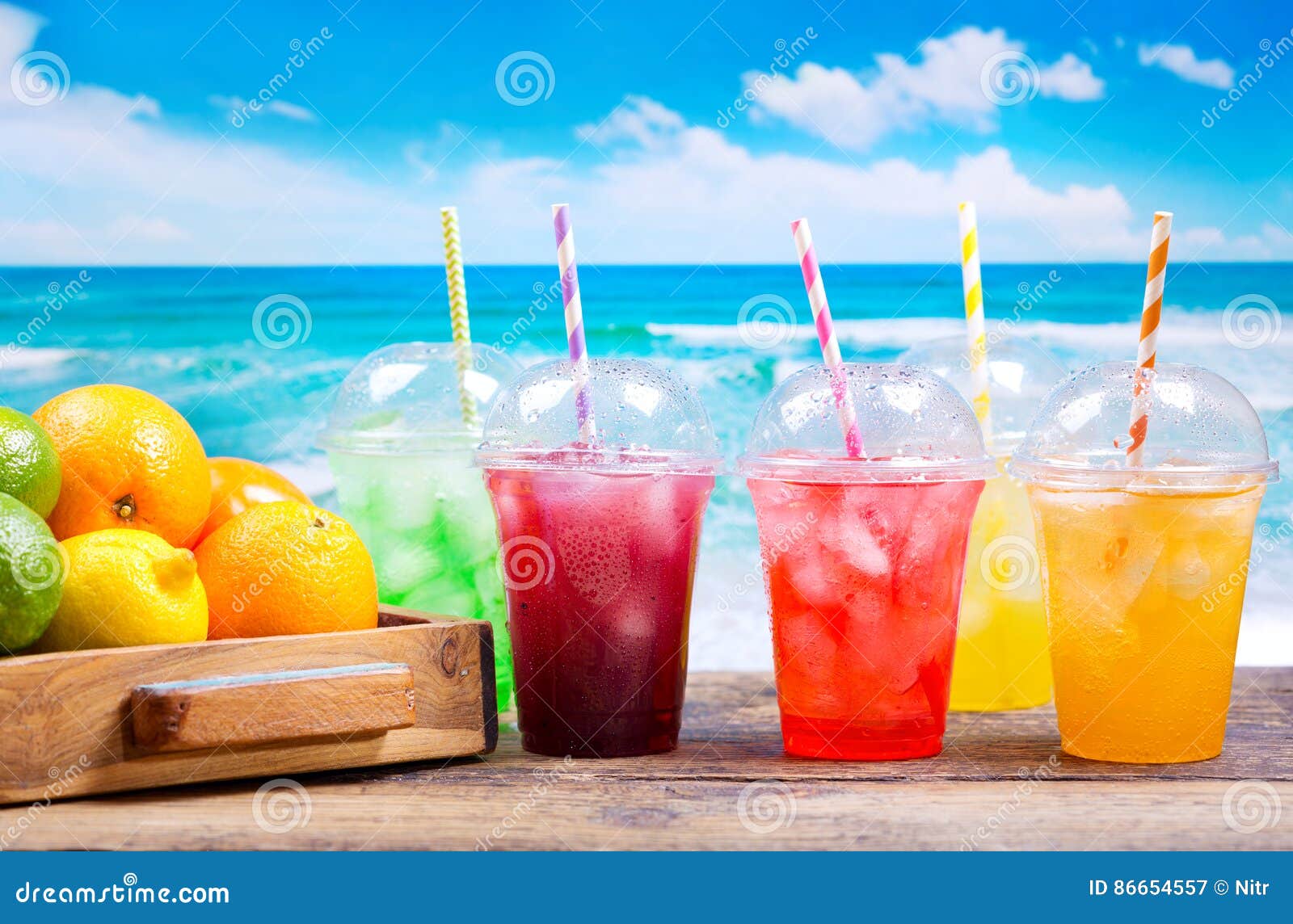 colorful cold drinks in plastic cups on the beach
