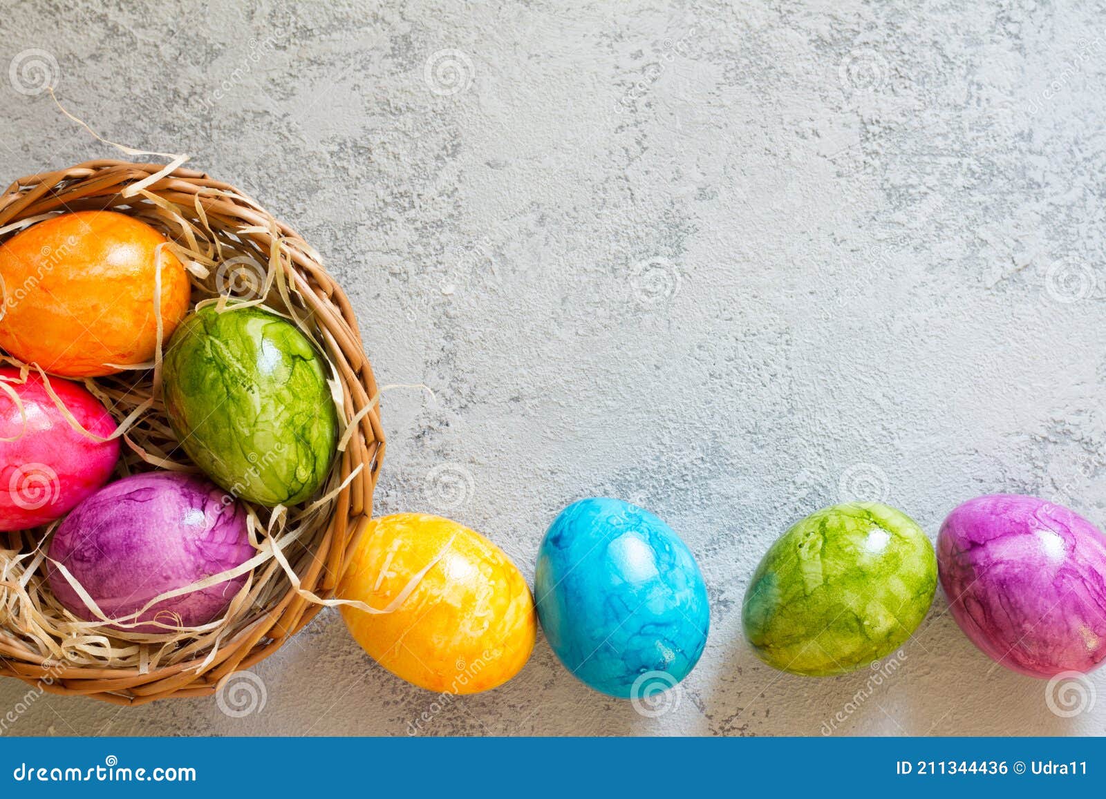 Colorful Easter Eggs in Basket on Concrete Background Stock Photo