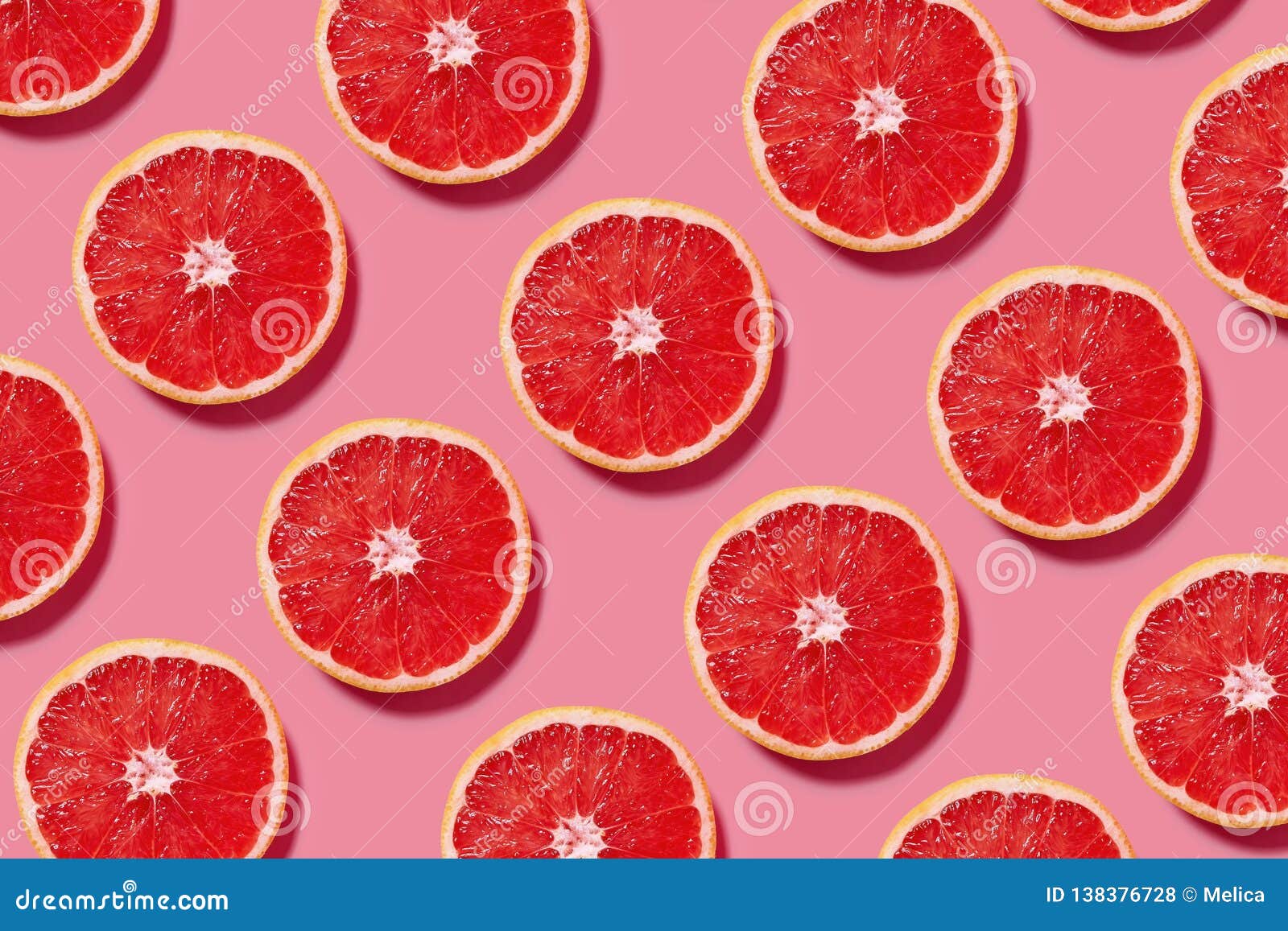 colorful fruit pattern of fresh grapefruit slices on pink background