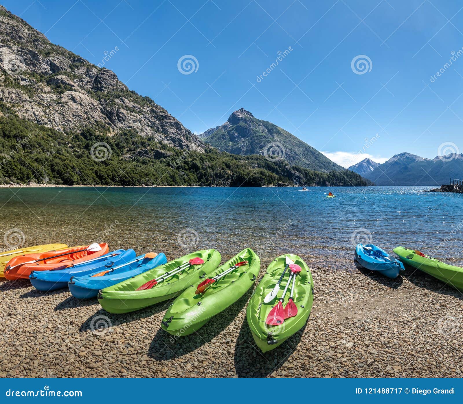 colorful kayaks in a lake surrounded by mountains at bahia lopez in circuito chico - bariloche, patagonia, argentina