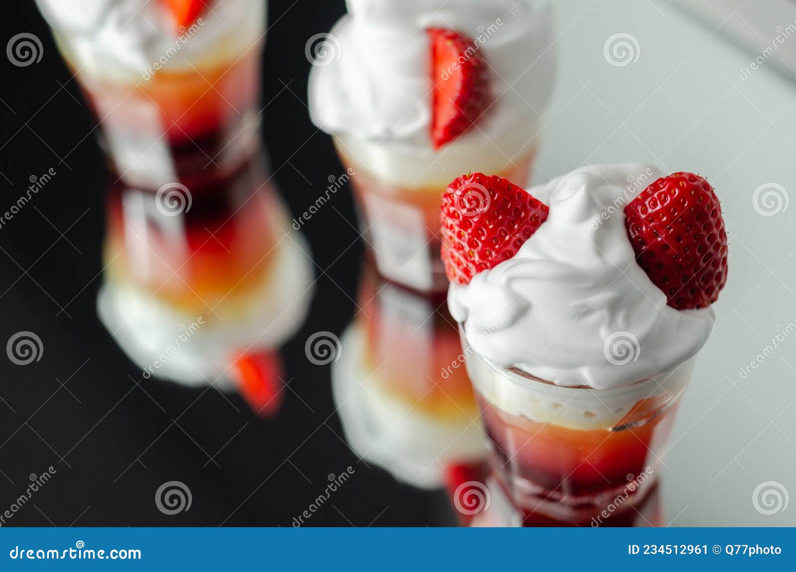 colorful layered shots of drinks based on vodka, grenadine and orange juice decorated with whipped cream and pieces of strawberry