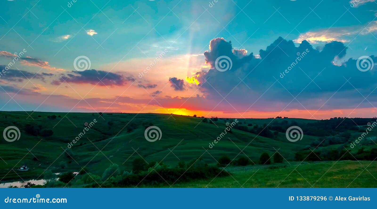 colorful orange sunset on green hills with a calming blue sky durig a warm summer