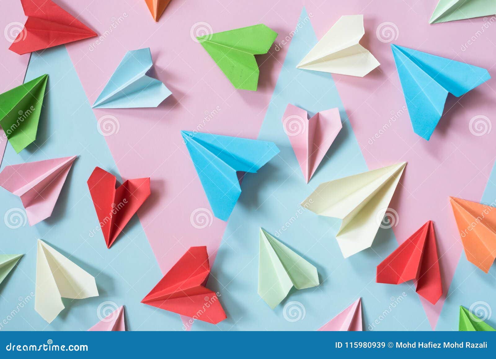 colorful paper airplanes on pastel pink and blue colored background