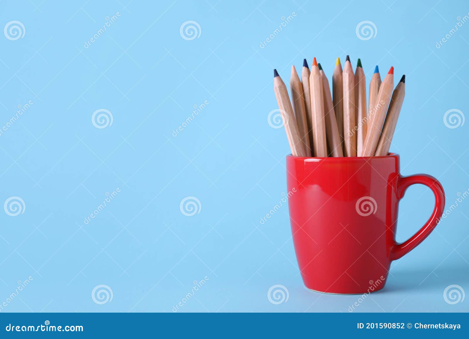 Colorful Pencils in Cup on Light Blue Background. Space for Text Stock