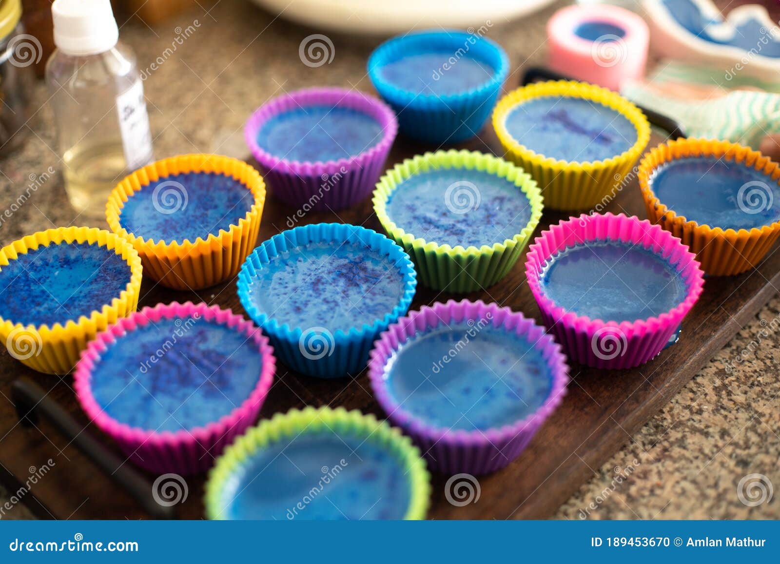 colorful silicon cupcake molds on wooden coard filled with liquid soap for a home made hobby of melt and pour soapmaking