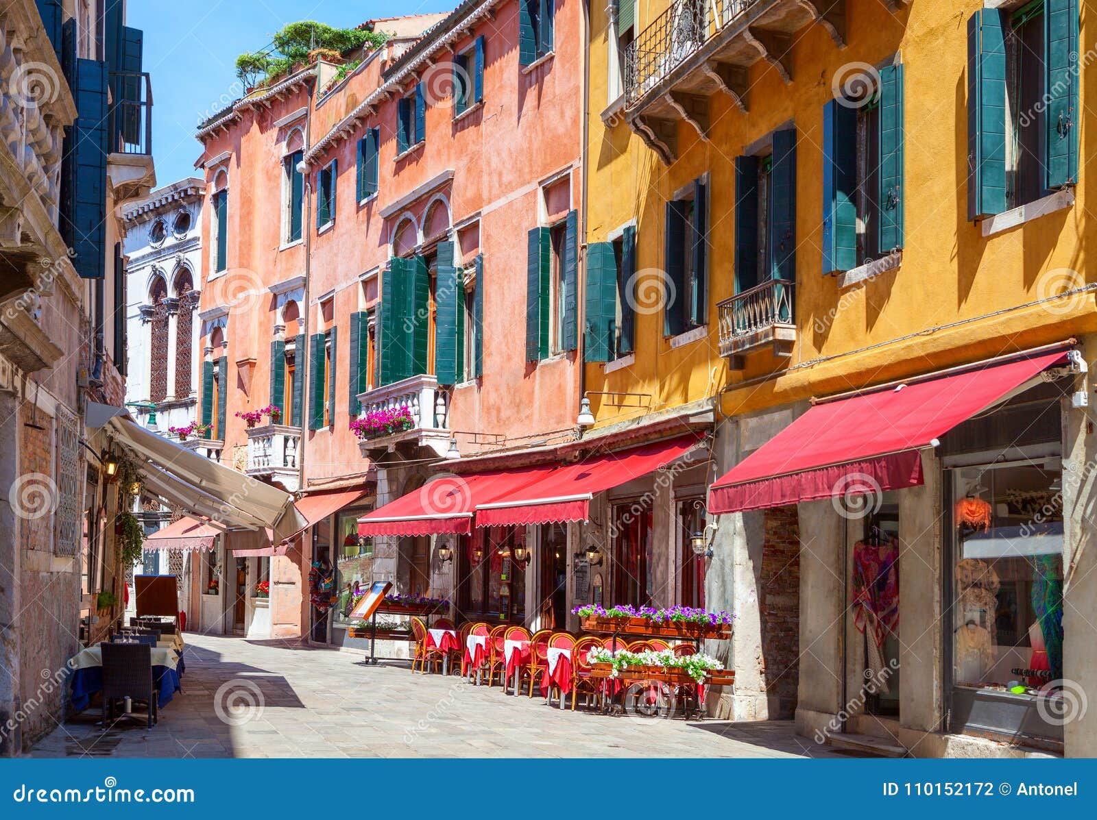 colorful street with tables of cafe at a sunny morning, venice, italy