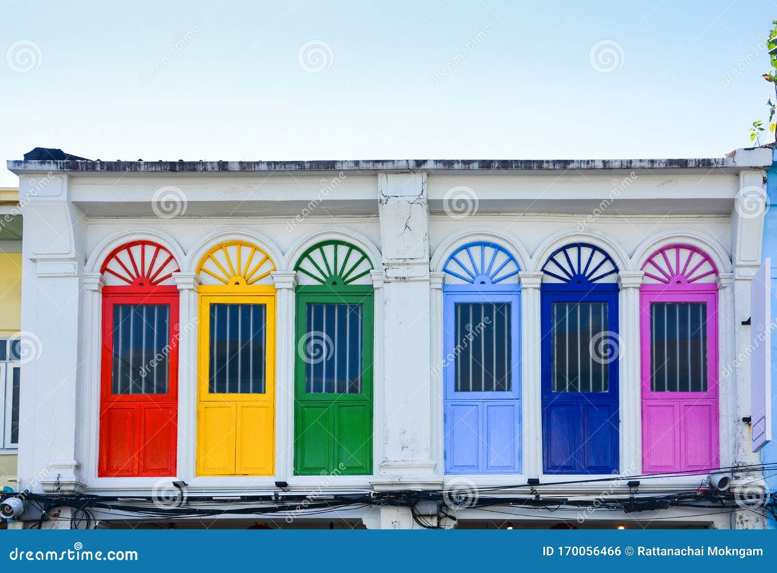 colorful wooden arched window on white cement wall in chino portuguese style at phuket old town, thailand