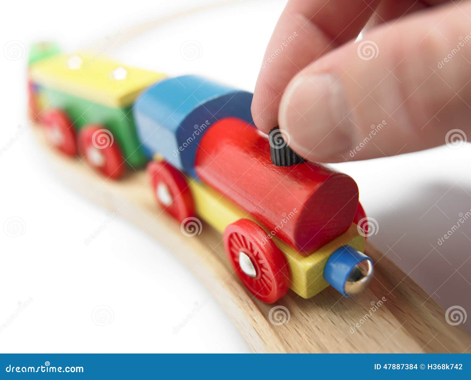 Colorful wooden toy train with hand isolated on white. Horizontal