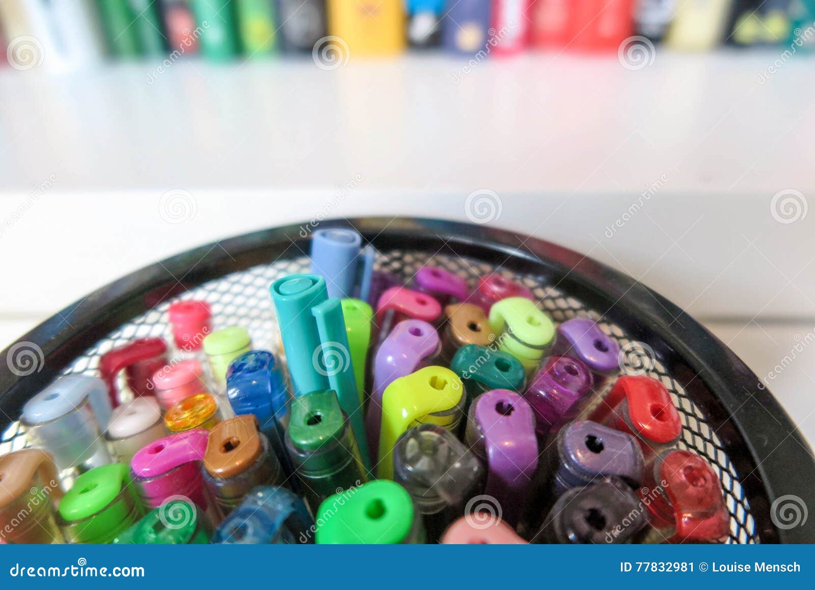 Coloring Pens In Mesh Container Against Blurred Bookshelf Stock