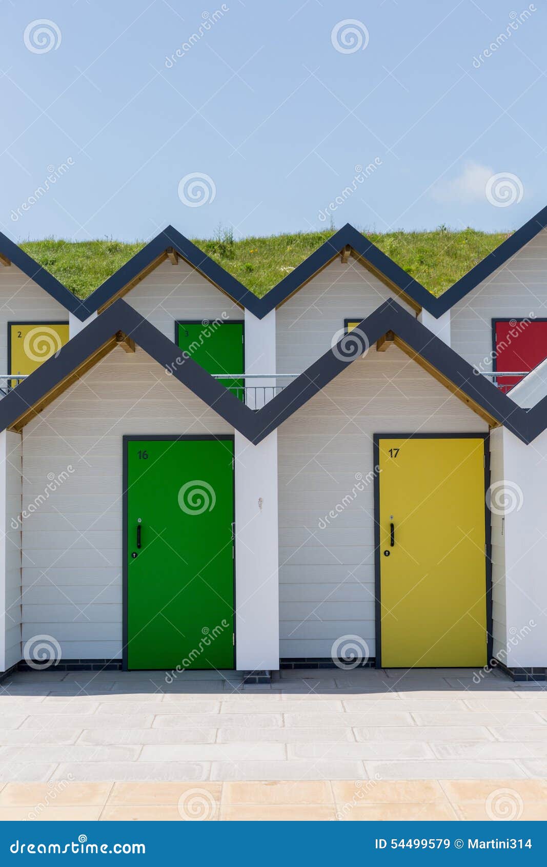 Colourful doors of yellow and green, with each one being numbered individually, of white beach houses on a sunny day in Swanage, Dorset, England