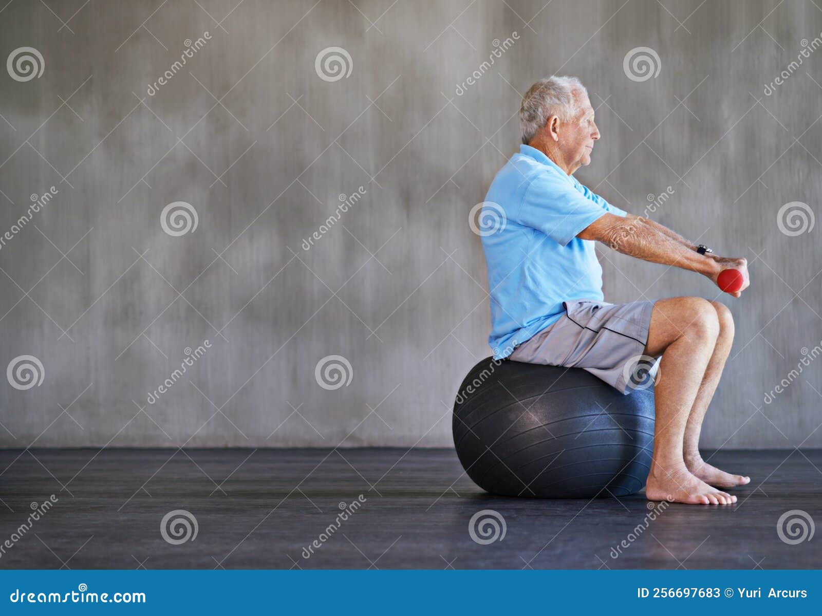 Combatting Aging. an Elderly Man Using Weights while Sitting on a Swiss