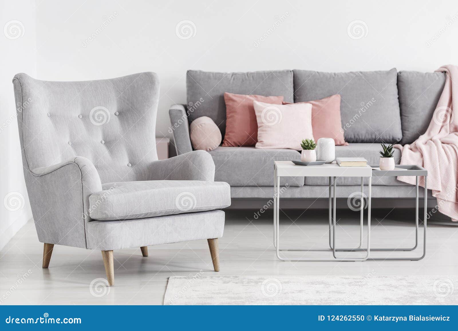 comfy armchair and grey sofa with pink pillows, and coffee table