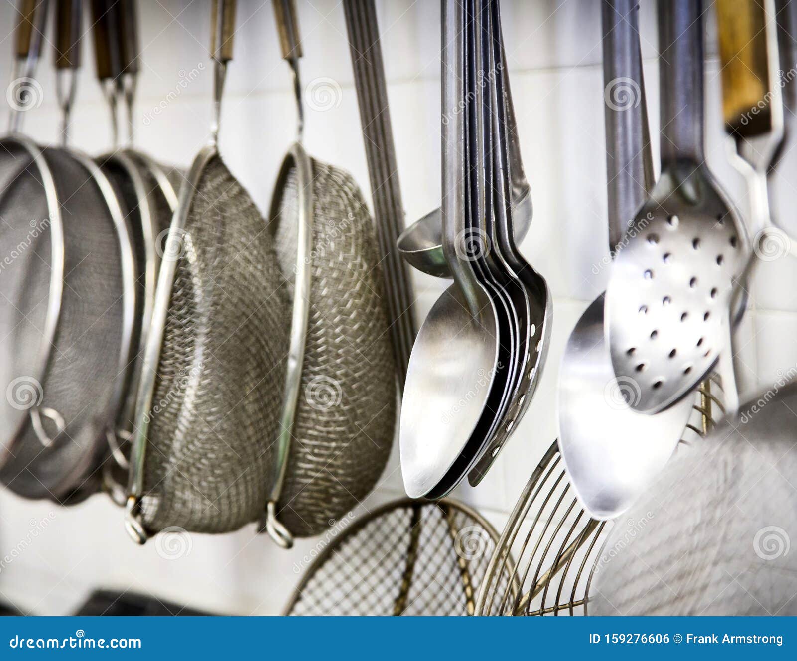 Commercial Kitchen Utensils Hanging on a White Wall Stock Photo Image