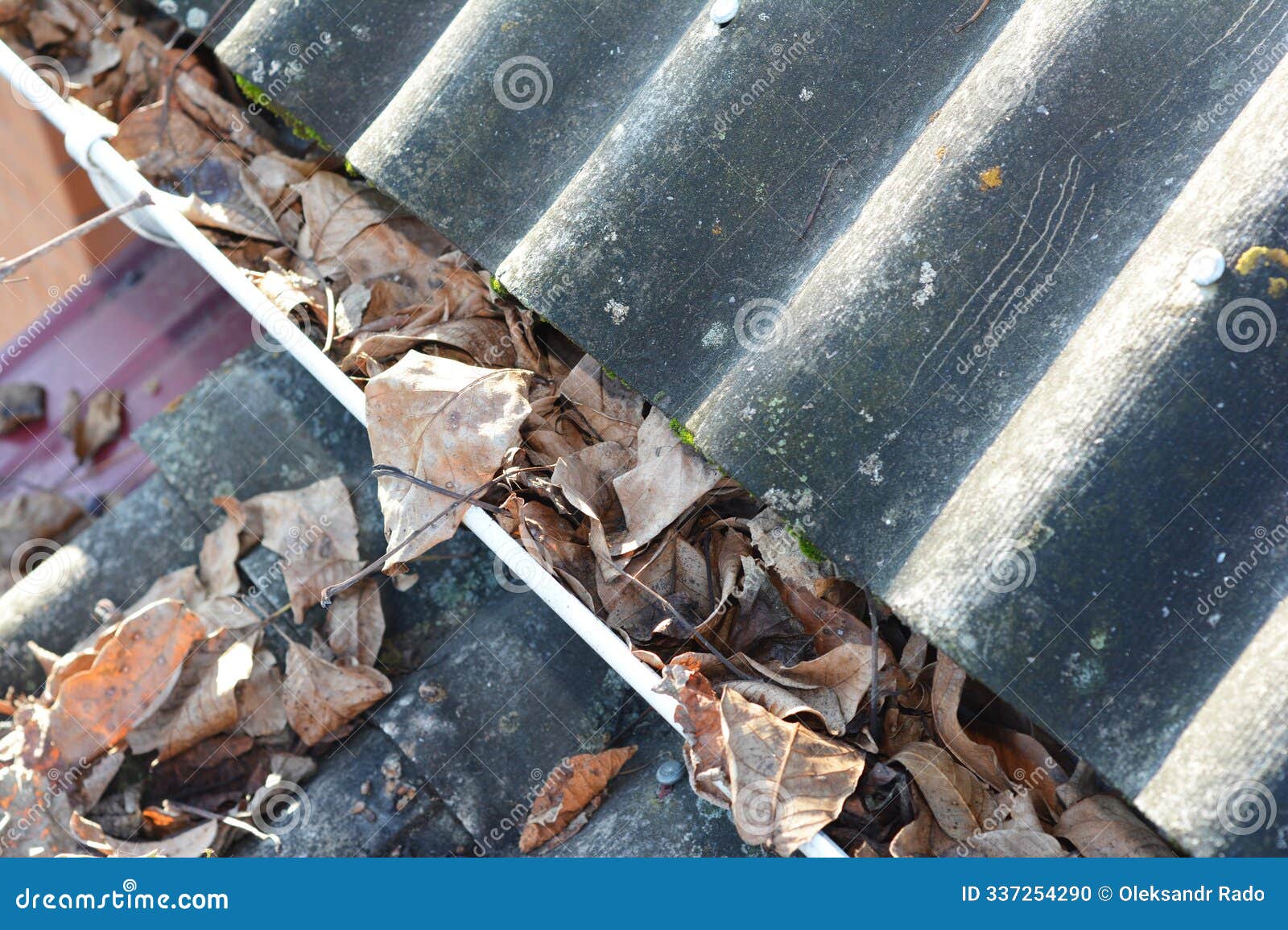 common problem caused by clogged gutters with autumn leaves. unclog gutters and clean downspouts. house asbestos roof and rain